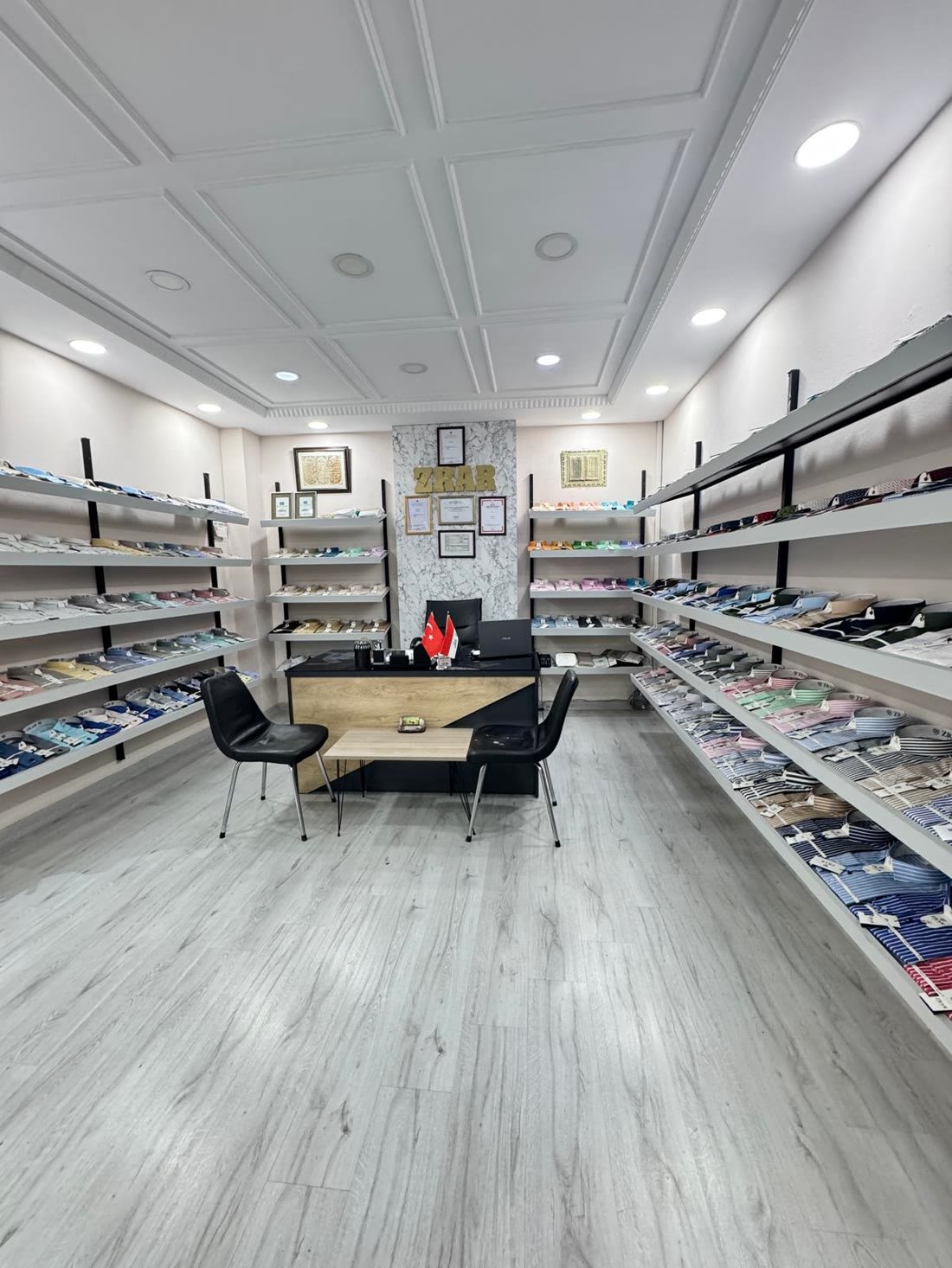 Showroom içi — iki yanda renklerine göre dizilmiş katlı gömlek rafları